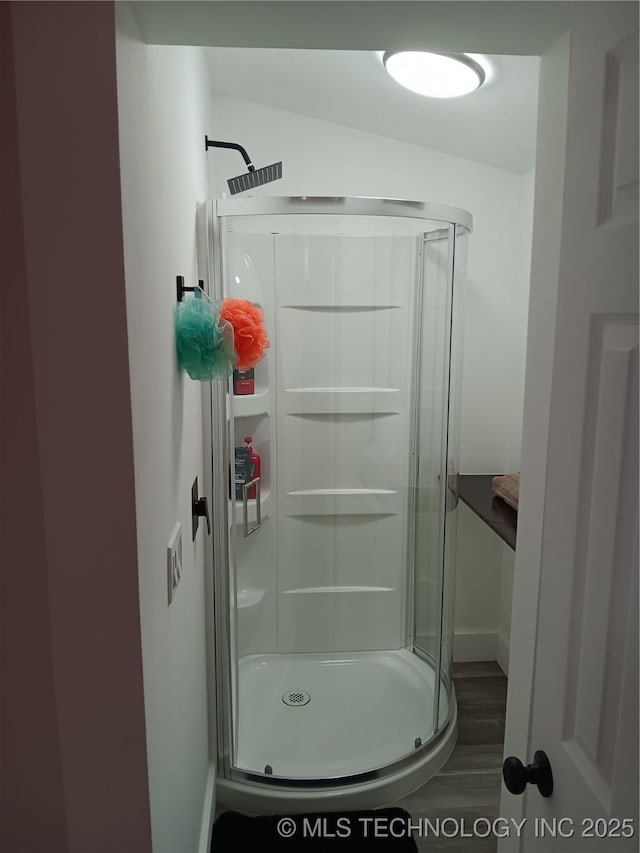 bathroom with a stall shower and wood finished floors