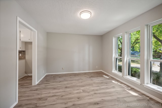 unfurnished room with a textured ceiling and light wood-type flooring