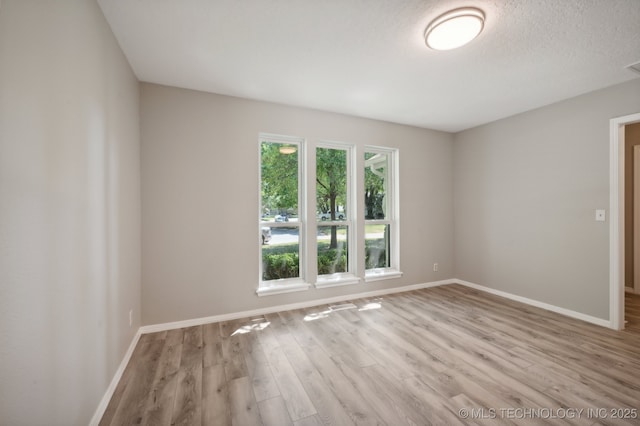 unfurnished room with light hardwood / wood-style flooring and a textured ceiling