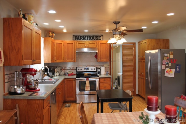 kitchen with decorative backsplash, appliances with stainless steel finishes, ceiling fan, sink, and light hardwood / wood-style floors