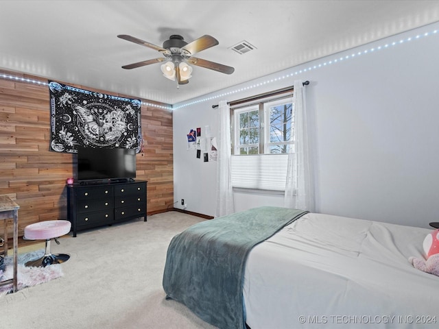 carpeted bedroom with ceiling fan and wood walls