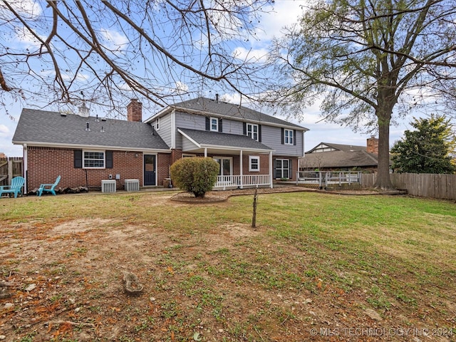 rear view of house featuring central AC and a yard