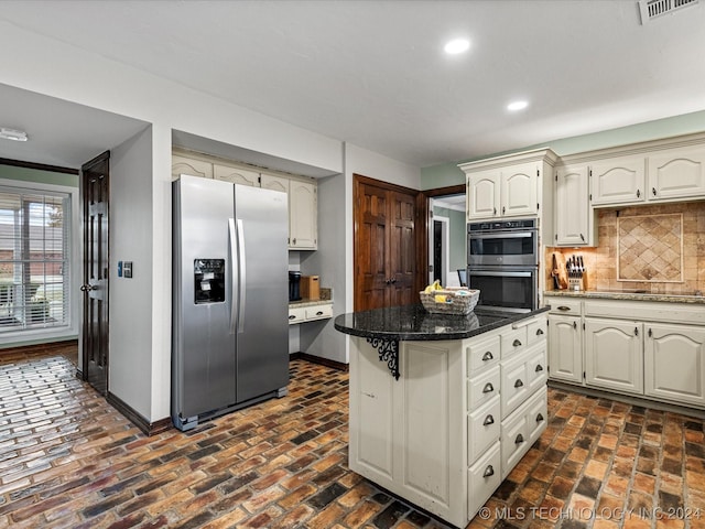 kitchen featuring backsplash, dark stone countertops, a kitchen bar, and appliances with stainless steel finishes