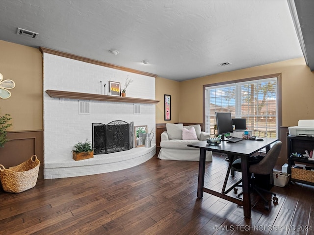 office with a textured ceiling, dark wood-type flooring, and a brick fireplace