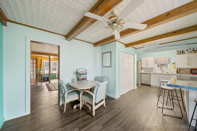 dining area featuring ceiling fan, sink, dark hardwood / wood-style flooring, beamed ceiling, and crown molding