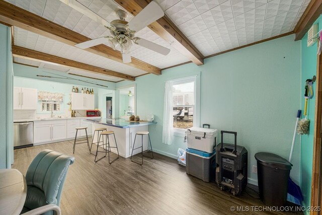 kitchen featuring a kitchen breakfast bar, sink, light hardwood / wood-style flooring, stainless steel dishwasher, and white cabinetry