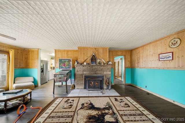 living room with a fireplace, hardwood / wood-style floors, and wooden walls