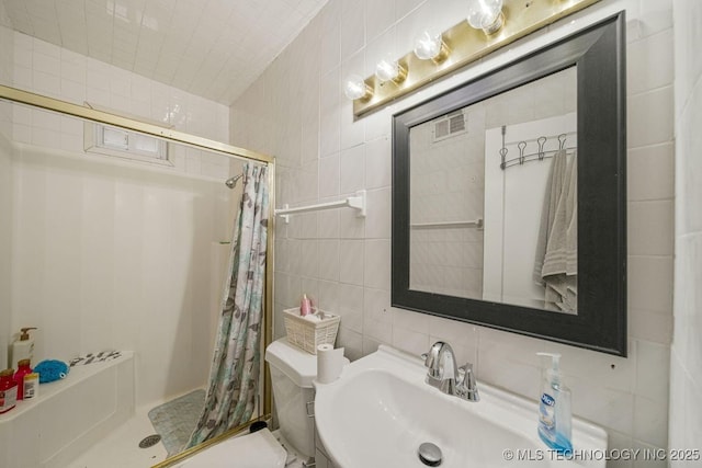 bathroom featuring a shower with curtain, toilet, sink, and tile walls