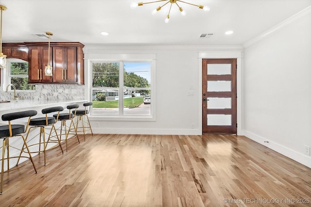 interior space featuring a chandelier, sink, crown molding, and light hardwood / wood-style flooring