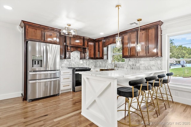 kitchen with a healthy amount of sunlight, stainless steel appliances, kitchen peninsula, pendant lighting, and a kitchen bar