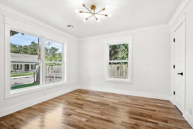 unfurnished room with hardwood / wood-style flooring, crown molding, and an inviting chandelier