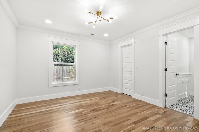 empty room featuring a chandelier, hardwood / wood-style flooring, and crown molding