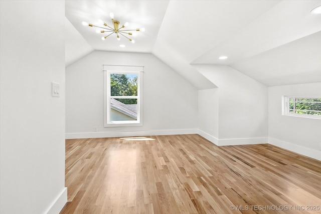 bonus room with a notable chandelier, plenty of natural light, light wood-type flooring, and vaulted ceiling