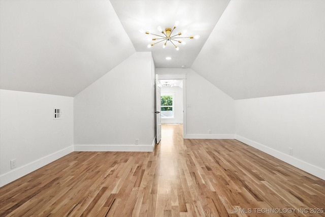 additional living space with light hardwood / wood-style floors, lofted ceiling, and a notable chandelier