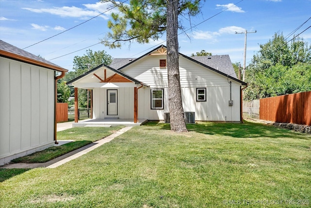 rear view of house featuring central AC and a lawn