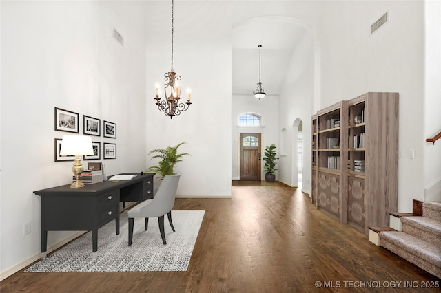 interior space with dark hardwood / wood-style flooring, a towering ceiling, and an inviting chandelier