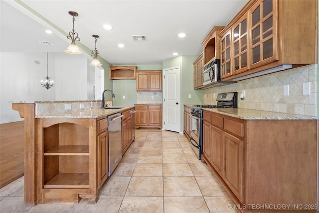 kitchen featuring light stone countertops, appliances with stainless steel finishes, tasteful backsplash, sink, and hanging light fixtures