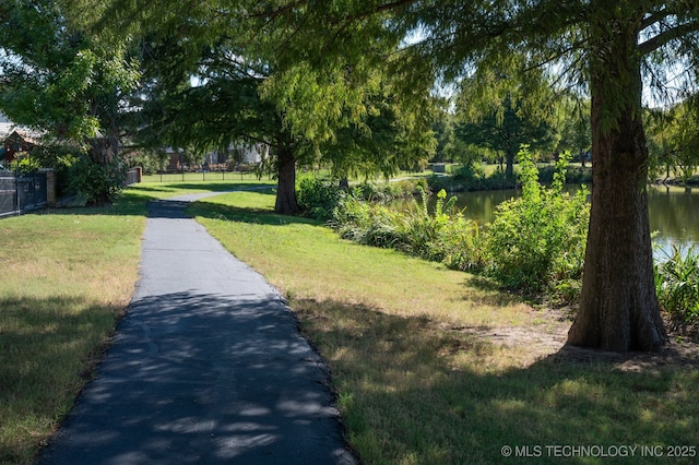 view of property's community with fence, a yard, and a water view