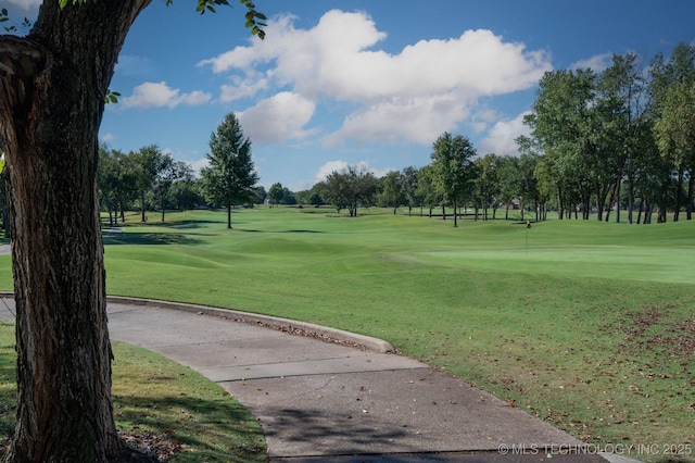 view of property's community with golf course view and a lawn