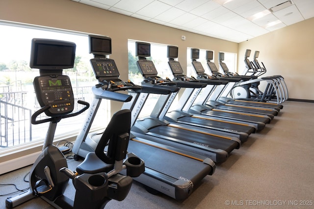 exercise room with a drop ceiling and a healthy amount of sunlight