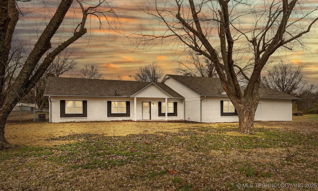 ranch-style home featuring central AC unit and a lawn