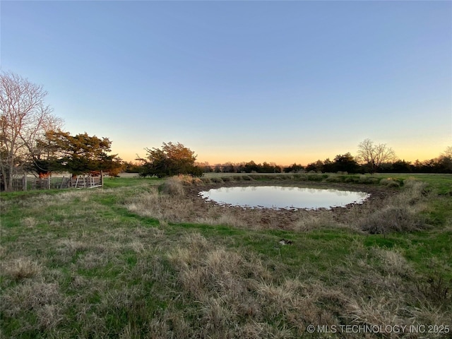 yard at dusk featuring a water view