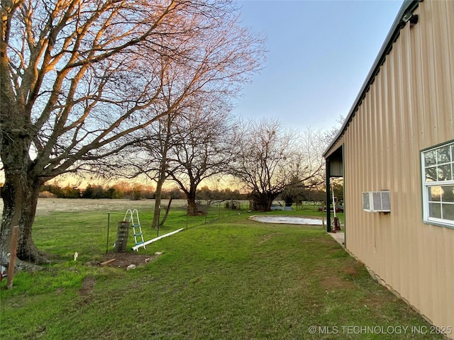 yard at dusk featuring an AC wall unit