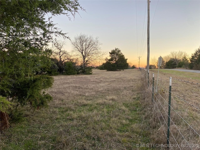 yard at dusk featuring a rural view