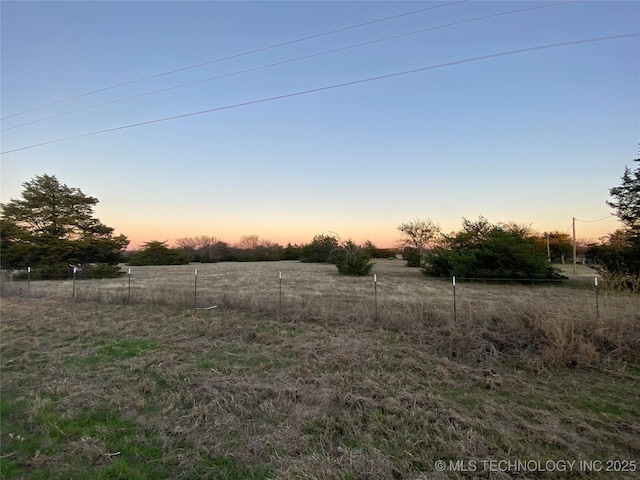 yard at dusk featuring a rural view