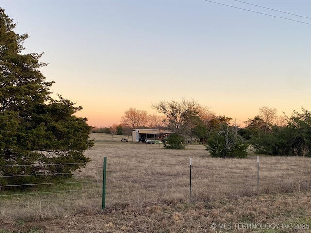 yard at dusk featuring a rural view