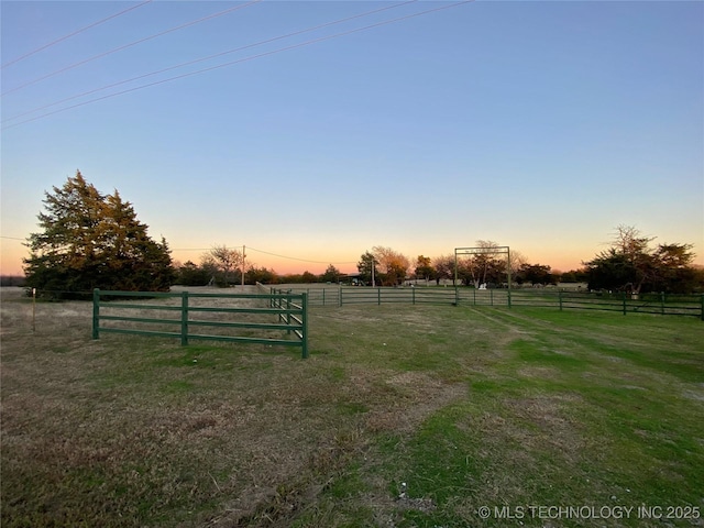 yard at dusk featuring a rural view