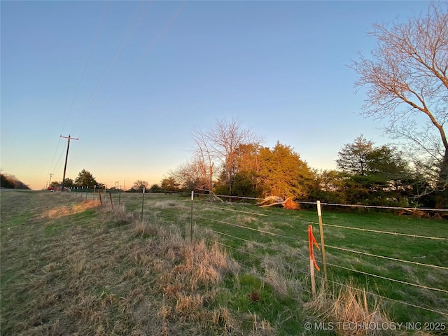 yard at dusk featuring a rural view