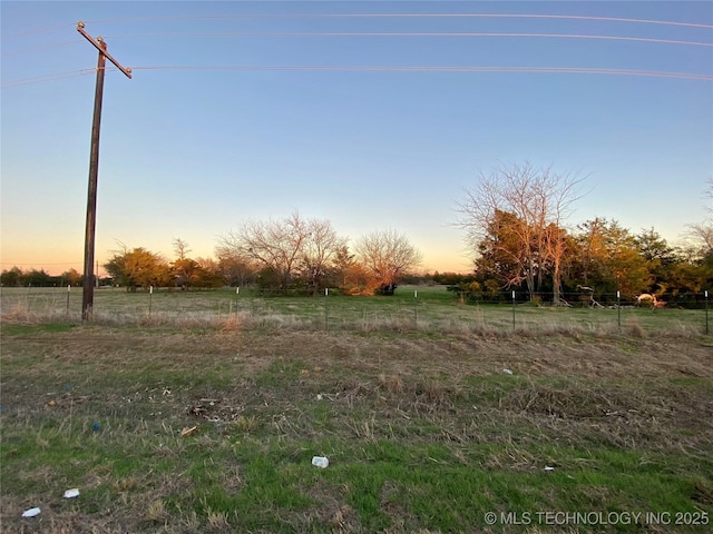 yard at dusk featuring a rural view