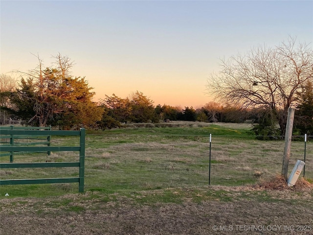 yard at dusk featuring a rural view