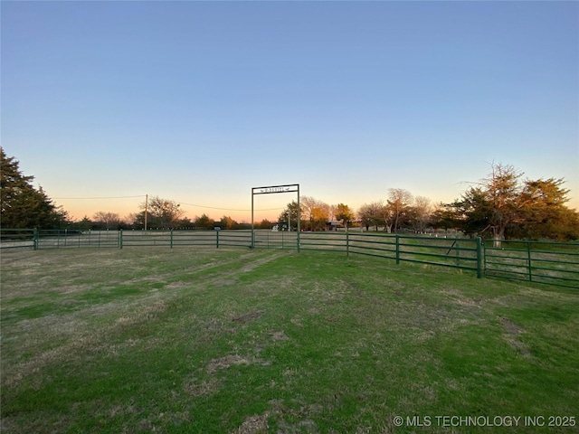 yard at dusk featuring a rural view