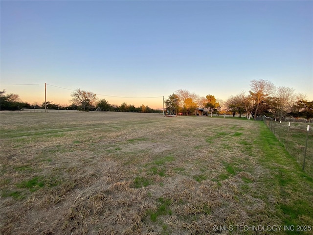 yard at dusk featuring a rural view