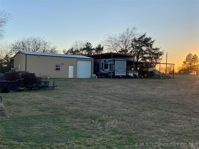 yard at dusk featuring an outbuilding, a garage, and a carport