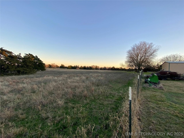 yard at dusk featuring a rural view