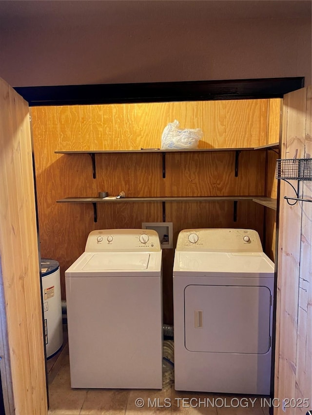 laundry area with independent washer and dryer, light tile patterned floors, and wood walls