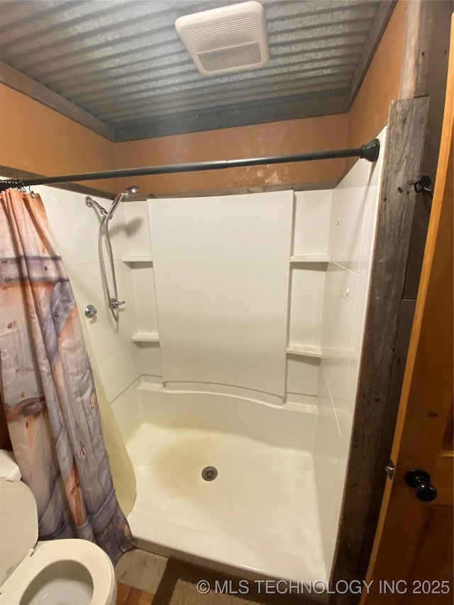 bathroom with toilet and a shower with shower curtain