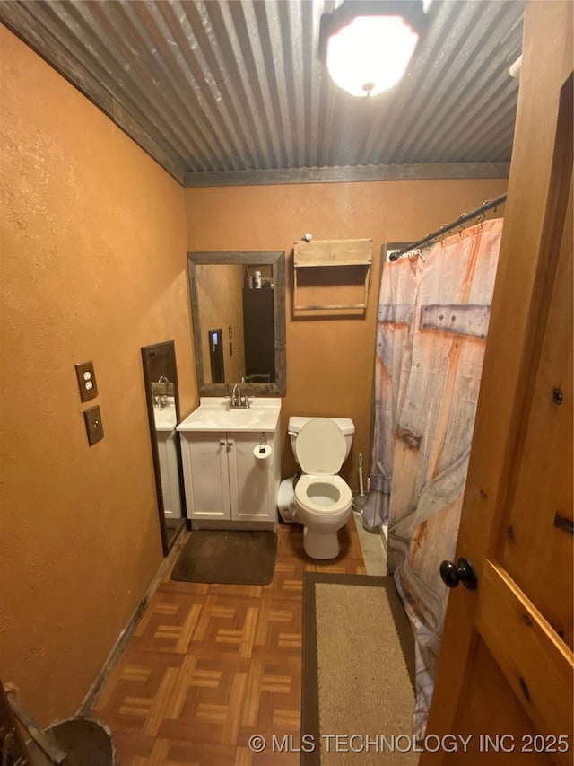 bathroom featuring vanity, toilet, and parquet floors