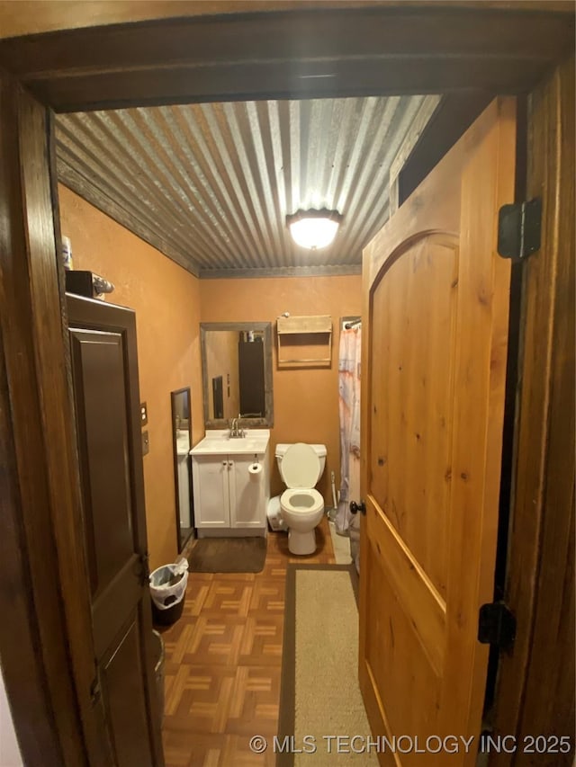 bathroom featuring toilet, vanity, and parquet flooring