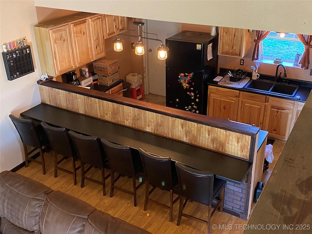 591 Peanut Trl, Hendrix, OK 74741 - kitchen featuring a sink, freestanding refrigerator, light wood-style flooring, dark countertops, and a kitchen bar