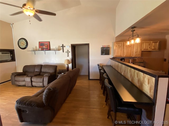 living room featuring ceiling fan, light hardwood / wood-style floors, and vaulted ceiling