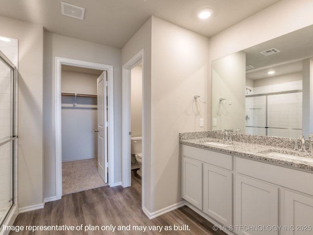 bathroom featuring hardwood / wood-style flooring, toilet, and a shower with shower door