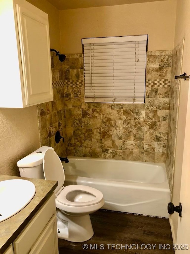 full bathroom with hardwood / wood-style floors, vanity, toilet, and tiled shower / bath