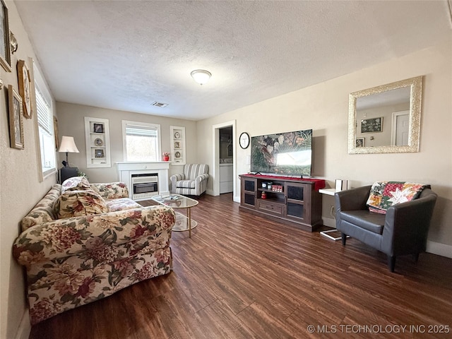 living room with a textured ceiling and dark hardwood / wood-style floors