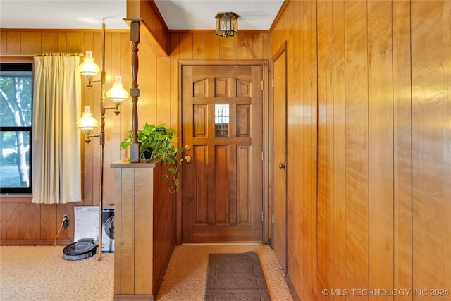 entryway featuring carpet, crown molding, and wooden walls