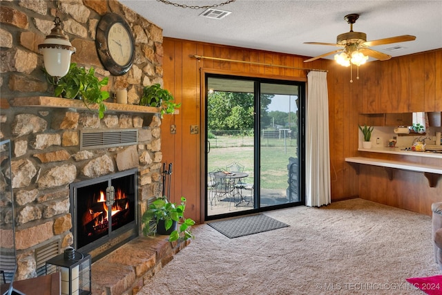 interior space with a fireplace, wood walls, a textured ceiling, and ceiling fan