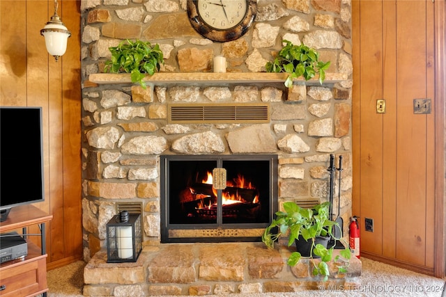 interior details with carpet flooring, a stone fireplace, and wooden walls